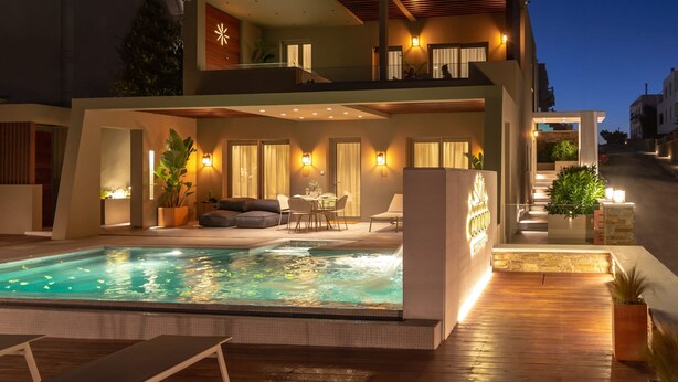 A modern two-story building with a swimming pool, outdoor seating, and warm lighting. - Coocono Tinos Private Villas (Tinos)