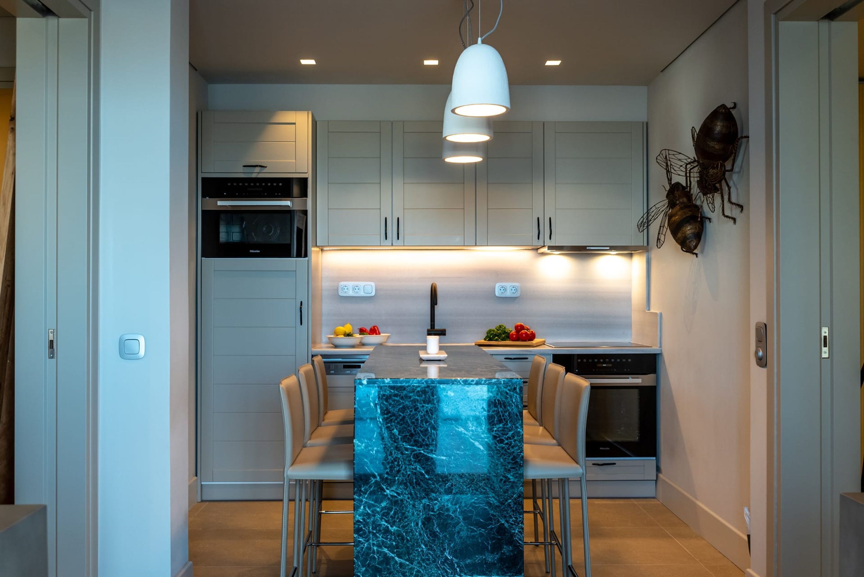 A modern kitchen with a central island, white cabinetry, and stainless steel appliances.