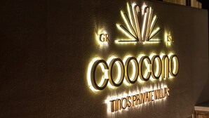 A modern building with a prominent illuminated sign reading "COOCONO TINOS PRIVATE VILLAS". - Coocono Tinos Private Villas (Tinos)