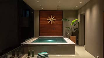 A modern spa area with a wooden wall, a glowing star-shaped light, a glass-enclosed hot tub, and a plant.