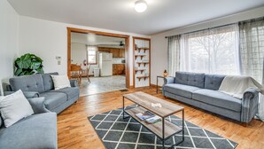 Ein Wohnzimmer mit grauem Sofa, einem Holztisch und einer großen Pflanze.