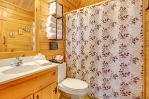 A wooden bathroom with a sink, toilet, and shower curtain. - Quaint Dahlonega Cabin w/ Cavenders Creek Access! (Dahlonega)