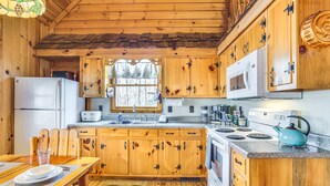A wooden cabin kitchen with a refrigerator, microwave, stove, and wooden cabinets. - Quaint Dahlonega Cabin w/ Cavenders Creek Access! (Dahlonega)