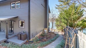 Une maison moderne à deux étages, dotée d’un porche couvert, d’un petit jardin et d’une clôture en bois.