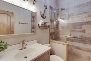 A modern bathroom with a large mirror, a sink, a toilet, and a glass shower enclosure. - Lakefront Townhome w/ Dock: 6 Mi to Blue Ridge! (Morganton)
