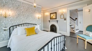 A bedroom with a bed, a chair, a fireplace, and a staircase. - Oceanfront Mid-Coast Maine Home w/ Private Beach! (Stockton Springs)