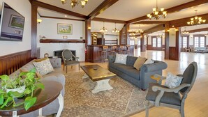 A spacious living area with a large sofa, armchairs, a coffee table, and a TV mounted on the wall.