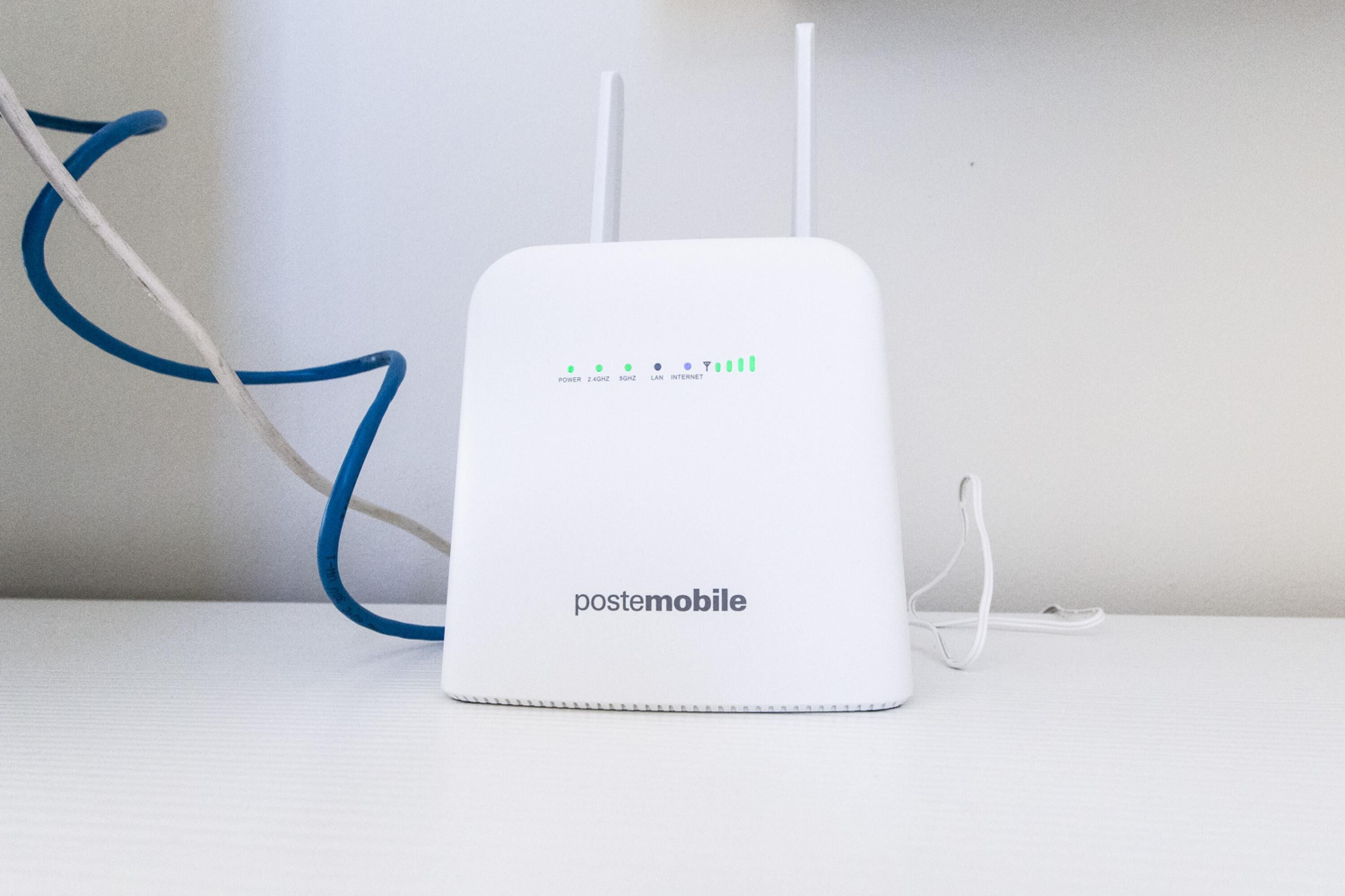 Un router postmobile bianco con due antenne e un cavo di alimentazione su una superficie bianca.