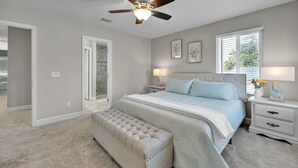 Une chambre à coucher avec un lit, un ventilateur de plafond, une table de chevet, un banc et une fenêtre.