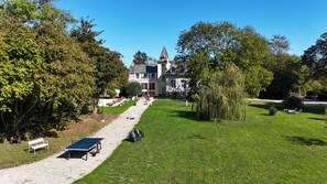 A large building with a prominent tower, surrounded by a well-maintained lawn and trees. - La Villa Mirabelle 2 min from Arromanches-les-Bains (Tracy-sur-Mer)