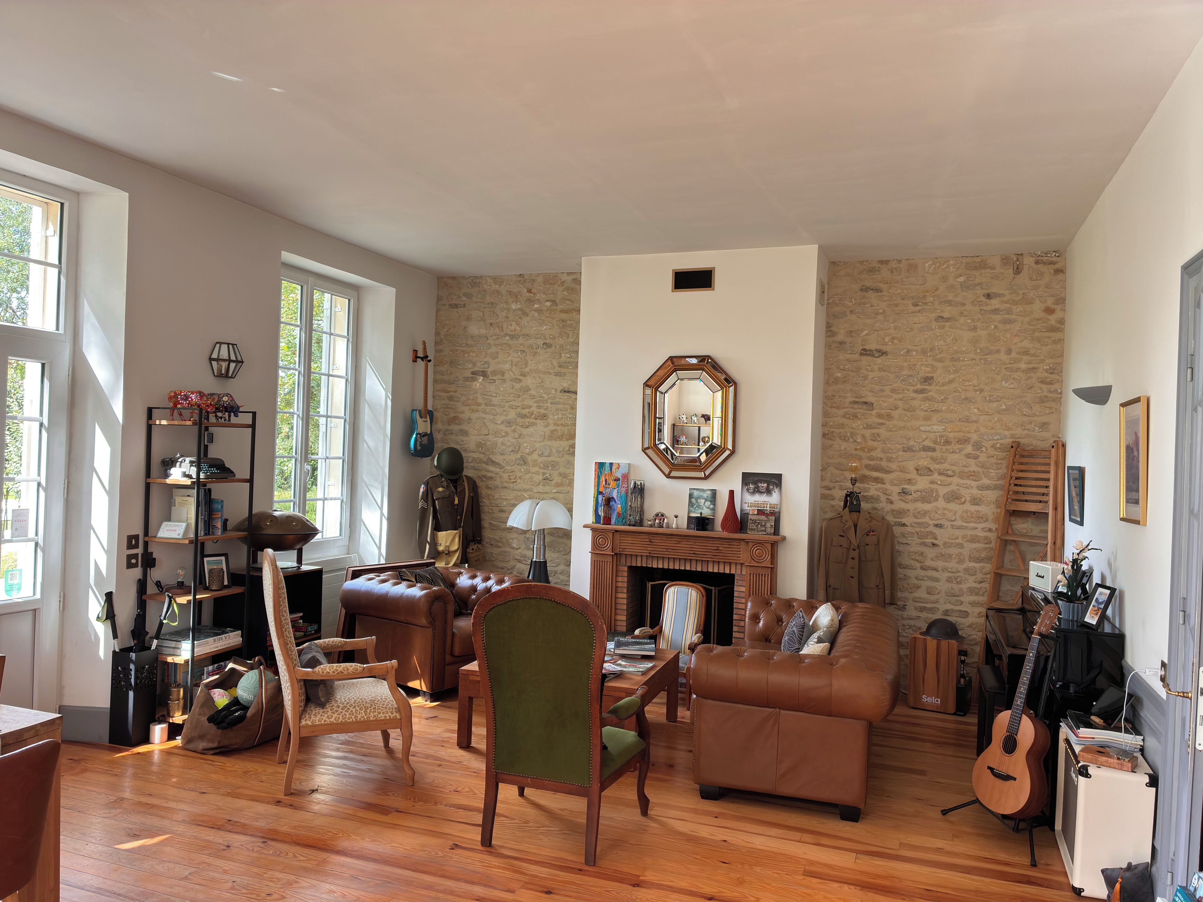 A cozy living room with a fireplace, wooden floors, and a stone wall.