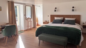 A modern bedroom with a wooden headboard, a large bed with a green blanket, a desk with a chair, and a large mirror. - LA VILLA MIRABELLE (Tracy-sur-Mer)