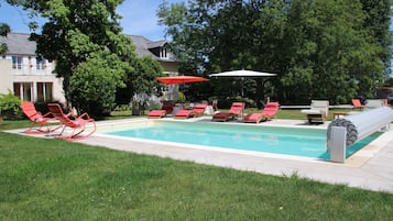 En sÀsongsöppen utomhuspool, parasoller och solstolar