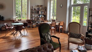 Ein geräumiges Zimmer mit Essbereich, einer Bücherwand und großen Fenstern.
