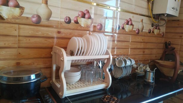 A kitchen with wooden paneling, a stove, a dish rack, and hanging pots.