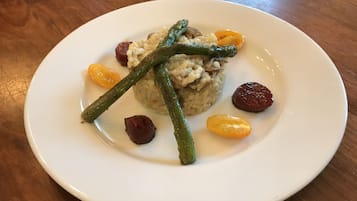 A plate of food with rice, green beans, and cherry tomatoes on a wooden table.