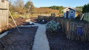 A garden with a gravel path, wooden fence, and a small shed. - VILLA L'ESTUAIRE (Braud-et-Saint-Louis)