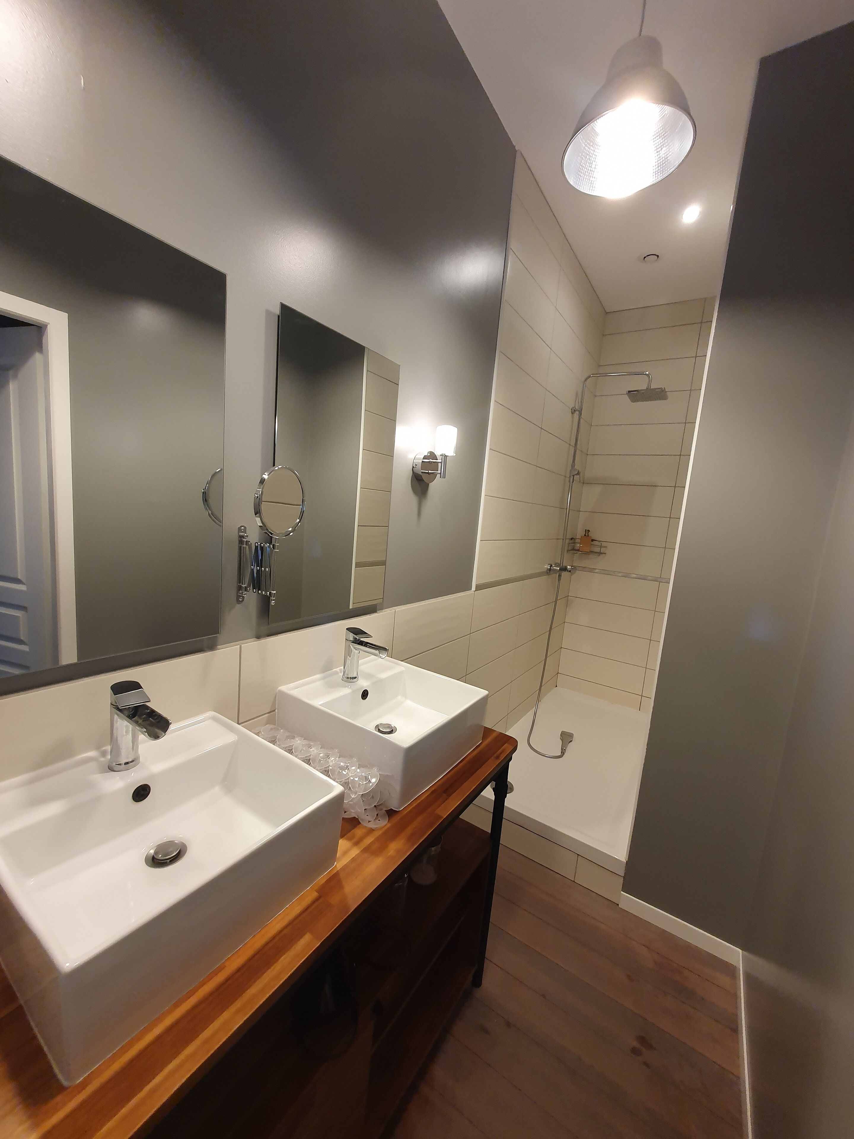 Uma casa de banho moderna com duas pias, um espelho grande e um chuveiro.