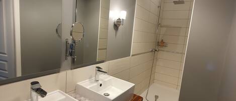 Un baño moderno con dos lavamanos, un espejo grande y una ducha.