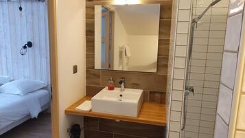 A modern bathroom with a wooden vanity, a large mirror, and a shower enclosure.
