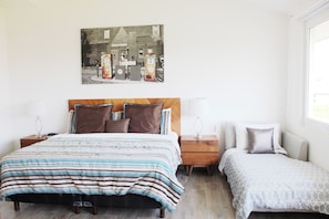 A bedroom with a bed, two bedside tables, a nightstand, a small table, and a wall-mounted picture. - New Villa 207 Deluxe , Golf Club, Punta Cala (Nuevo Nayarit)