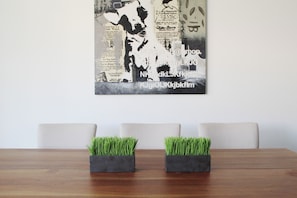 A dining table with two square planters of green grass, a white wall, and a black and white abstract artwork. - New Villa 207 Deluxe , Golf Club, Punta Cala (Nuevo Nayarit)