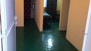 Ein schmaler Flur mit grünem Boden, der zu einem Zimmer mit einem Bett und einem Kleiderschrank führt.