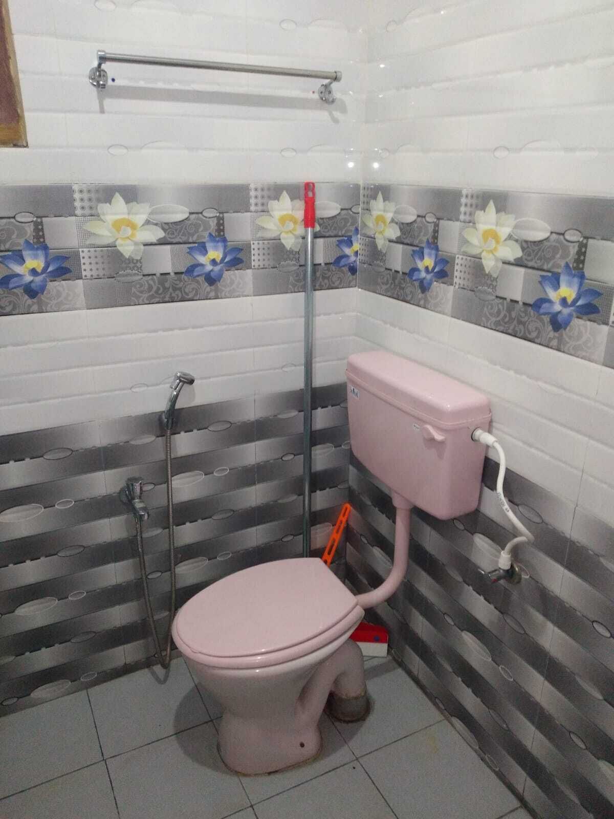 Un baño con inodoro, ducha y barra de apoyo.