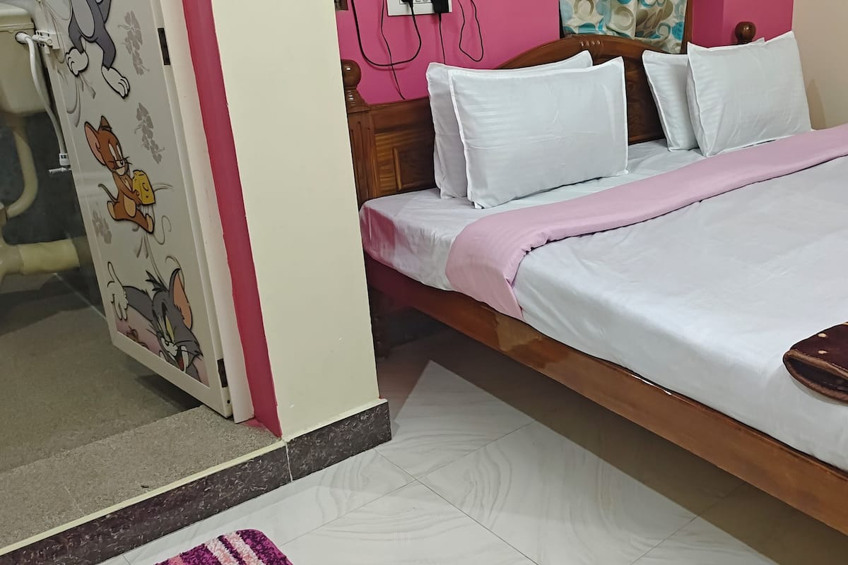 Quarto com cama, travesseiros, manta e parede decorada com personagens de desenho animado.
