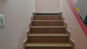 Un escalier en bois avec un interrupteur sur le mur, à gauche.
