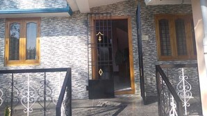 Une maison avec une façade en pierre, un portail en métal noir et une porte en bois.