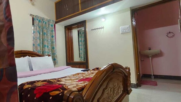Une chambre à coucher avec un lit, des rideaux, un miroir, un lavabo et une porte.