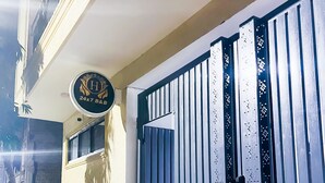 A gated entrance with a metal gate, a car parked in the driveway, and a building with a sign above the gate. - Roomshala 160 Hotel Red (New Delhi)