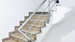 A modern staircase with metal railings and a white wall background. - Roomshala 160 Hotel Red (New Delhi)