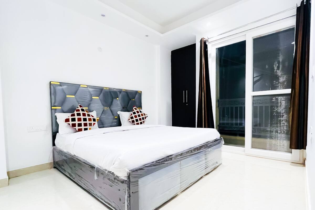 A bedroom with a bed, a black wardrobe, and a sliding glass door to the outside.