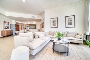 A spacious living area with a large L-shaped sofa, a round coffee table, and a dining area in the background. - Chic Beachside 3BR Living at the Palm (Dubai)