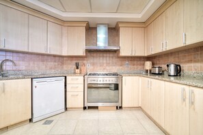 A kitchen with wooden cabinets, a stainless steel range hood, a built-in oven, and a dishwasher.