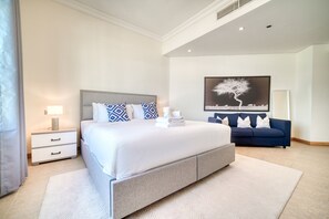 Ein modernes Schlafzimmer mit einem großen Bett, einem Nachttisch, einer Couch und einem Wandbild.