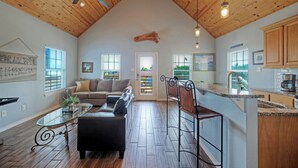 Un ampio loft con soffitto alto, travi in legno, zona pranzo, cucina e soggiorno con divano e tavolino.