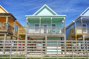 A row of beach houses with wooden balconies and a clear blue sky.