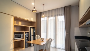 A modern kitchen with built-in appliances, a dining table, and chairs. - Anahata Home (Tabanan)