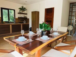 Enjoy meals in this stylish dining area with a long table for four, featuring white plates and clear glassware.