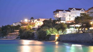 A coastal hotel with multiple balconies, a stone retaining wall, and a beachside view. - CLEAR HORIZON (Zakynthos)