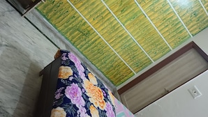 A room with a wooden ceiling, a floral-patterned bedspread, and a patterned wall.