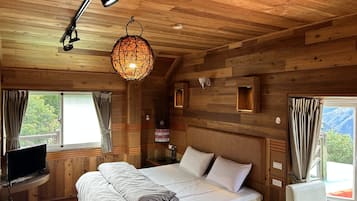 A wooden cabin bedroom with a bed, a television, and a hanging light fixture.