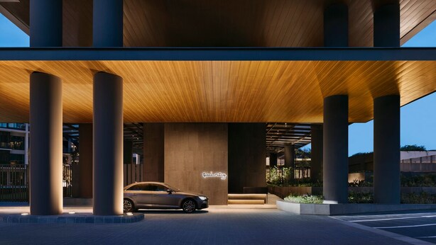A modern building entrance with a car parked under a wooden canopy. - Quincy House Singapore  (Singapore)