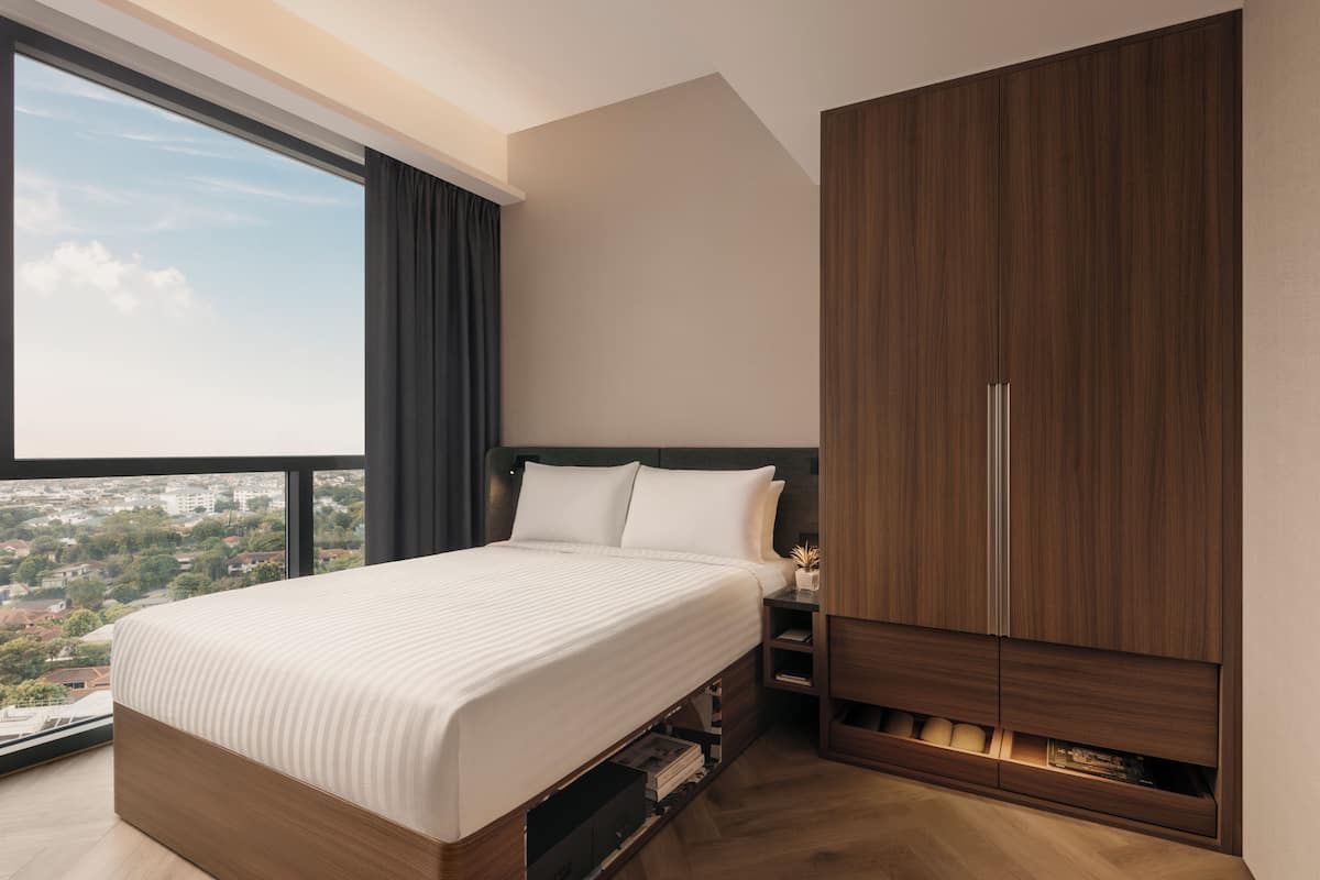 A modern bedroom with a large bed, a wardrobe, and a view of the city.