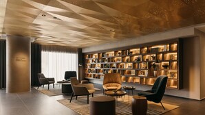A modern living room with a geometric ceiling, a bookshelf, and contemporary furniture. - Quincy House Singapore  (Singapore)