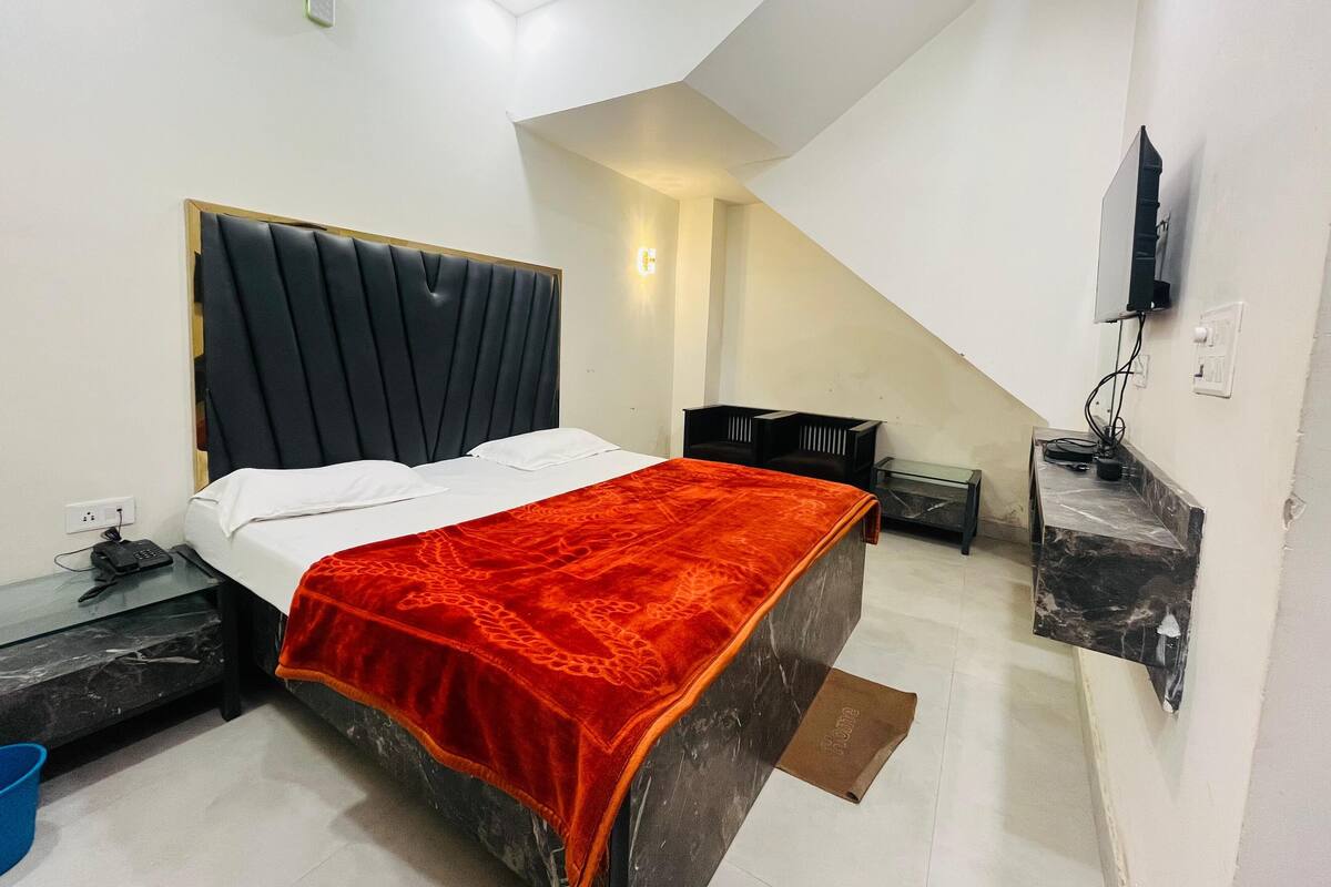 A bedroom with a bed, a nightstand, a TV, and a small table.