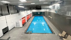 Ein Hallenbad mit deutlich markierten Bahnen, einem Sprungturm und Umkleideräumen mit Bänken.